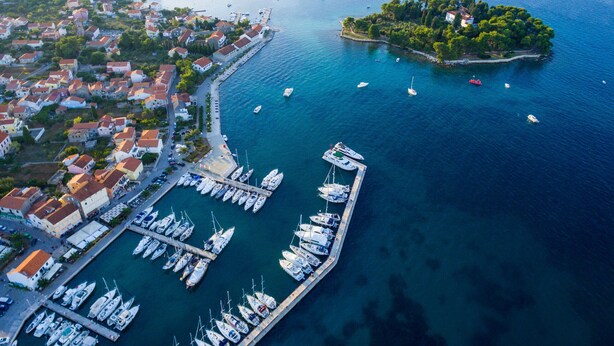 An aerial view of a coastal town with a marina, boats, and a small island.