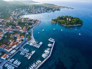 An aerial view of a coastal town with a marina, boats, and a small island.