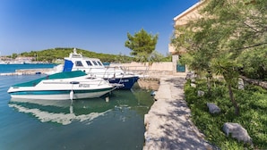 A marina with boats docked, a stone wall, and a building with a sloped roof.