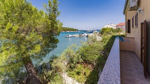 A coastal view with boats docked, a clear sky, and a building with a balcony overlooking the water.