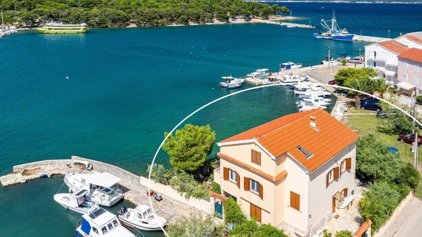 A coastal town with a marina, boats, and a prominent building with a red roof.