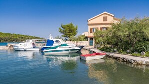 A marina with boats docked, a stone wall, and a building with a tiled roof.