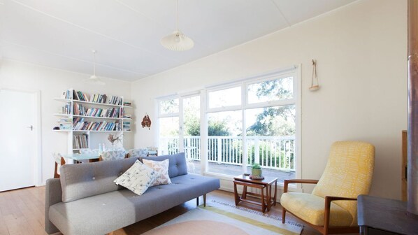 A living room with a sofa, armchair, bookshelf, and a window with a view.