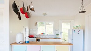A kitchen with a wooden countertop, white cabinets, a stove, and hanging pots. - Ipanema (Wye River)