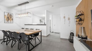Una cucina moderna con zona pranzo, che include un tavolo in legno, sedie nere e una lampada a sospensione.
