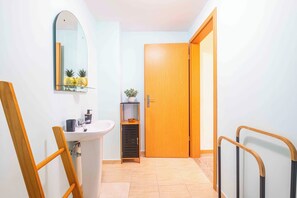 A bathroom with a sink, mirror, and a small shelf with a plant. - Santana House (Santana)