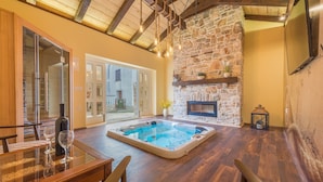 A spacious room with a stone fireplace, a hot tub, and a dining area with a glass table. - Villa Lemon ZadarVillas (Vir)