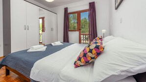 Ein Schlafzimmer mit Bett, Kleiderschrank, einem Fenster mit Vorhängen und einer Pendelleuchte.