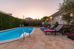 A swimming pool with lounge chairs and a stone patio.