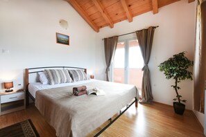 A bedroom with a bed, bedside tables, a night lamp, a potted plant, and a window with curtains. - Villa Smilje ZadarVillas (Slivnica)