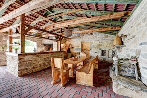 An interior with a stone wall, wooden beams, a brick floor, and a wooden table with chairs. - Villa Smilje ZadarVillas (Slivnica)