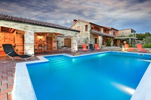 A pool area with lounge chairs and a stone building with a tiled roof. - Villa Smilje ZadarVillas (Slivnica)