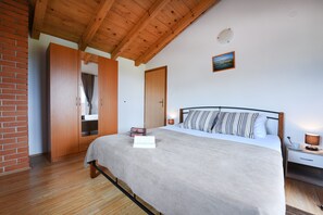 A bedroom with a bed, wooden wardrobe, and a nightstand with a lamp. - Villa Smilje ZadarVillas (Slivnica)