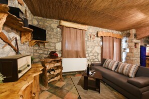 A rustic living room with a stone wall, wooden furniture, a television, a fireplace, and a sofa. - Villa Smilje ZadarVillas (Slivnica)