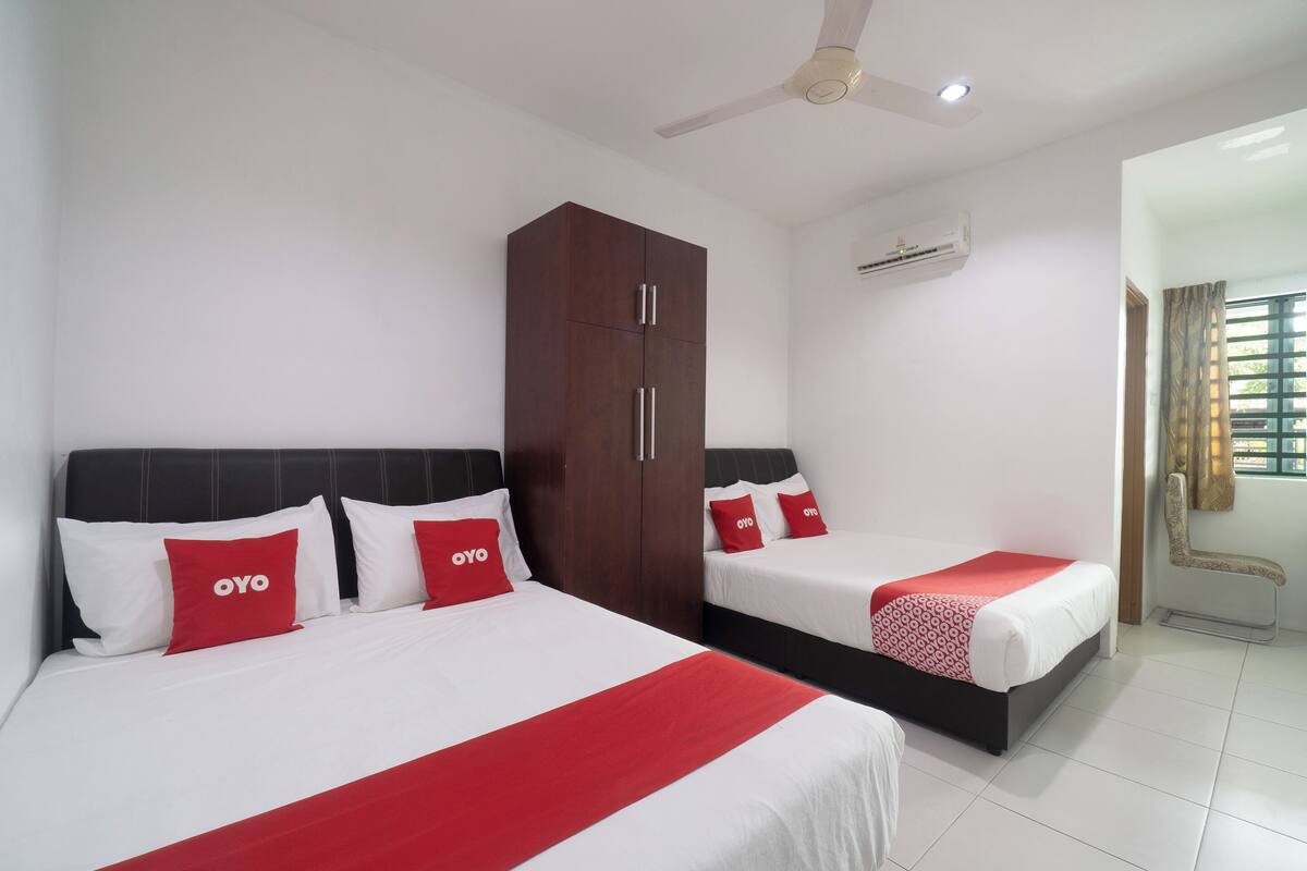 Une chambre d’hôtel avec deux lits, une armoire, un climatiseur et un ventilateur de plafond.