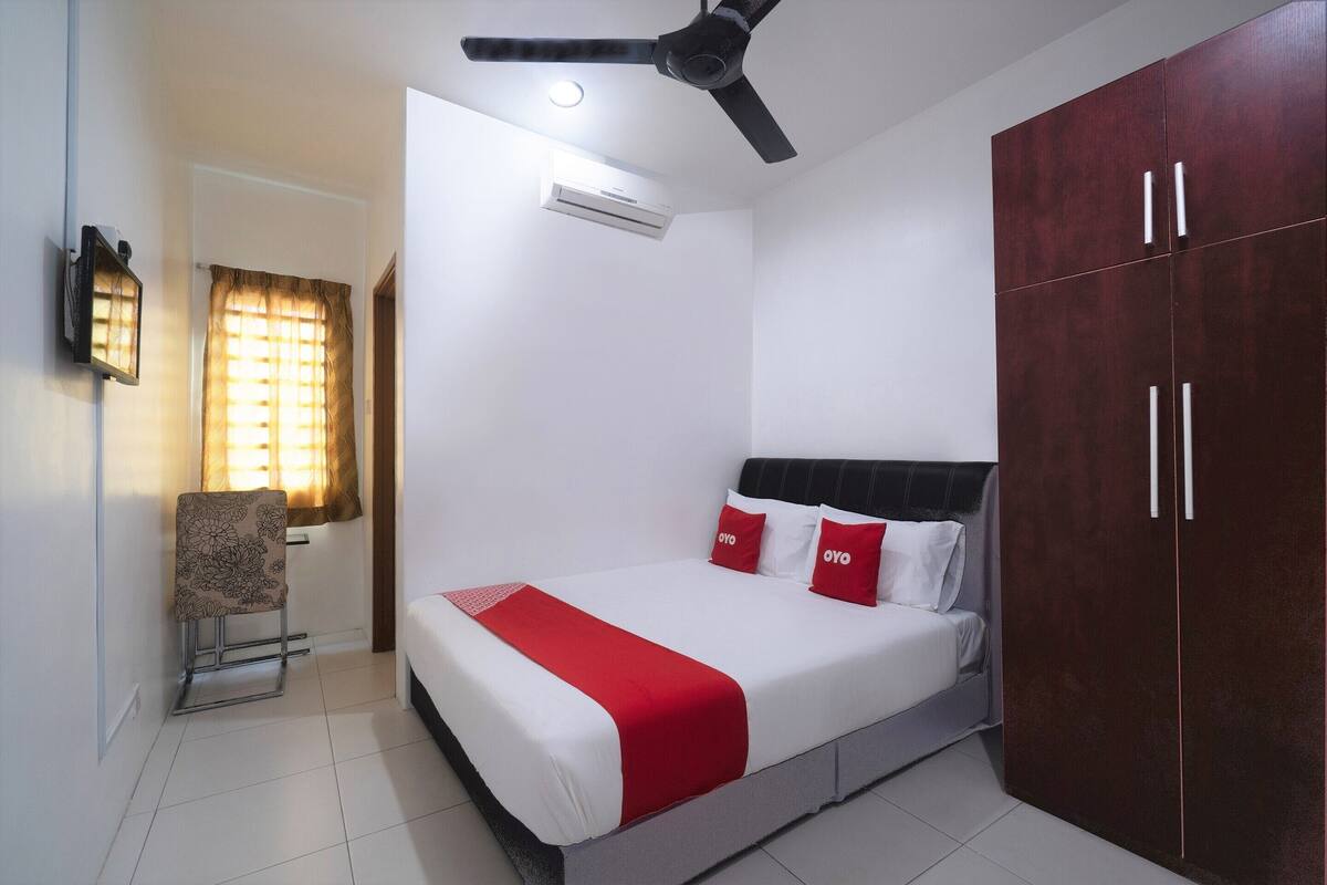 Une chambre comprenant un lit, une armoire, un ventilateur de plafond, un appareil de climatisation et une chaise.