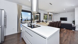A modern kitchen with a central island, a dining area with a table and chairs, and a living area with a sofa.