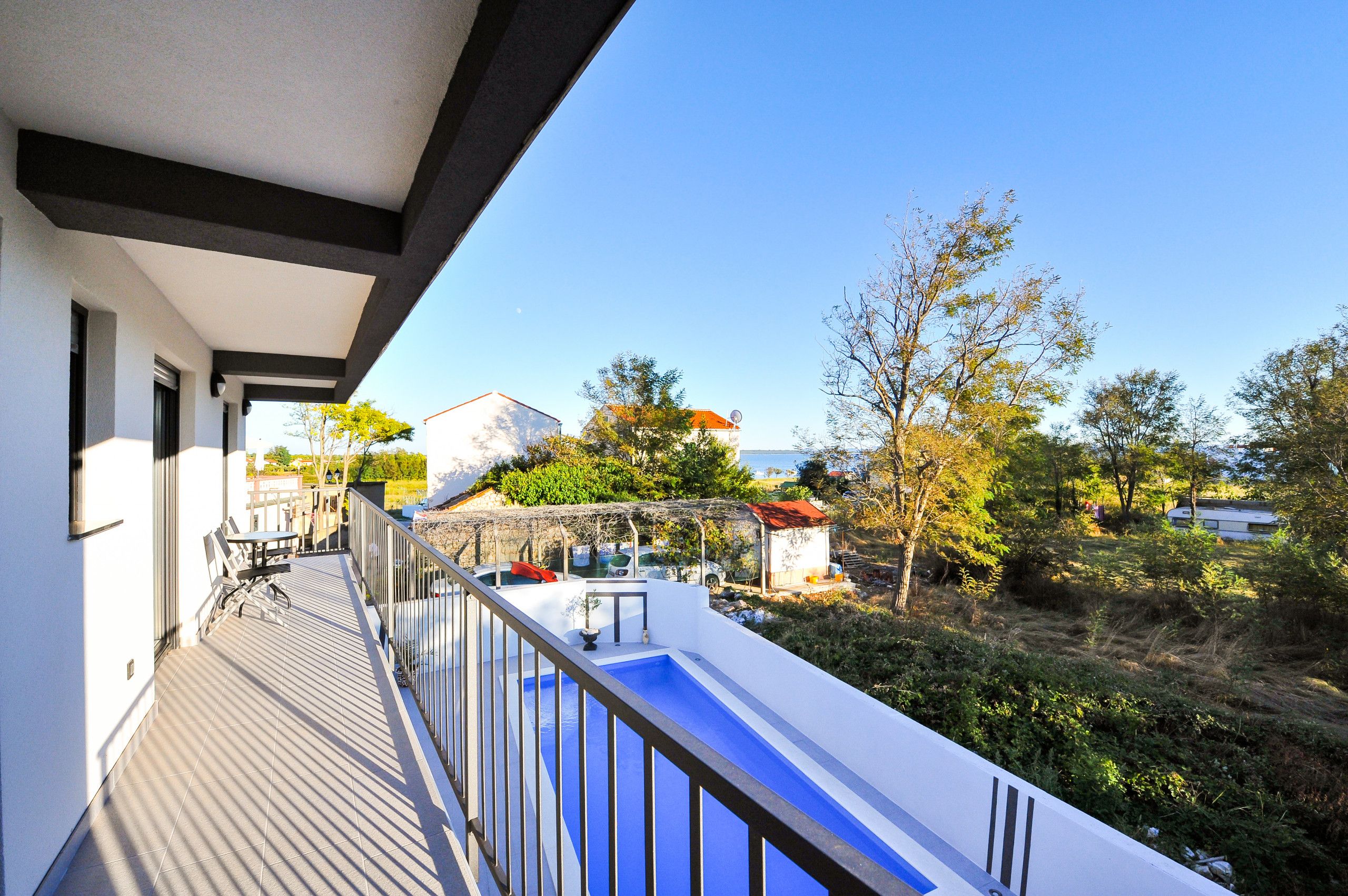 Un balcon donnant sur un jardin et des immeubles.