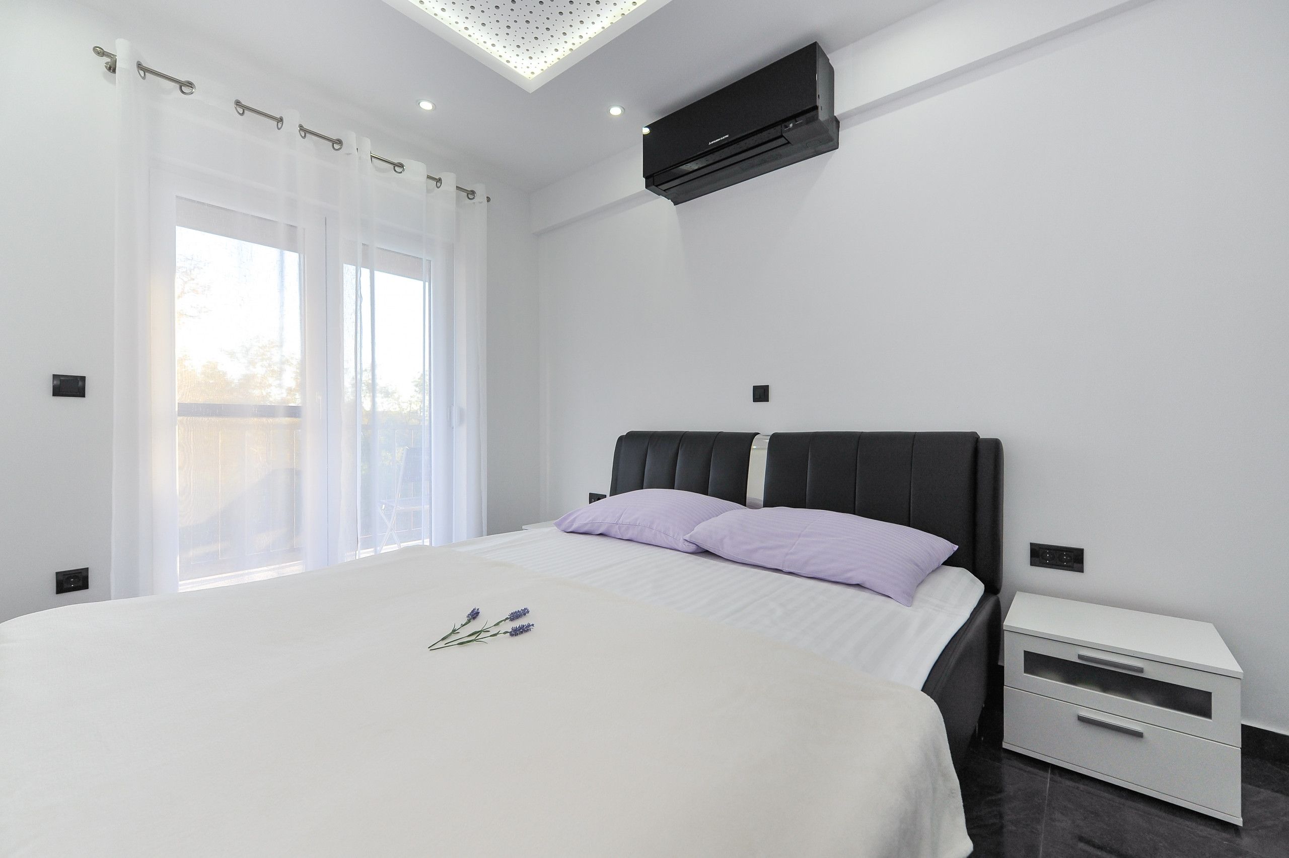 Une chambre moderne avec un grand lit, une table de chevet et un appareil de climatisation.