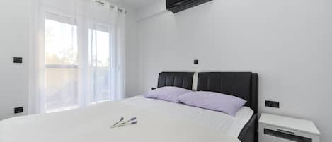 Un dormitorio moderno con una cama grande, una mesita de noche y un aire acondicionado.