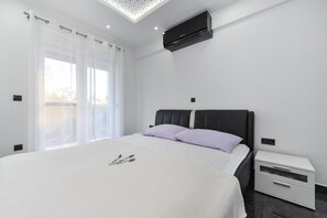 Quarto moderno com cama grande, mesa de cabeceira e ar condicionado.