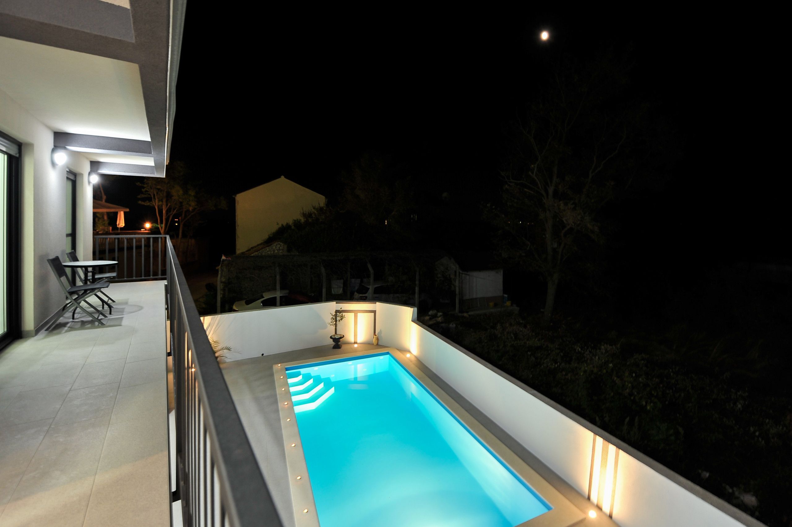 A rectangular swimming pool with a light blue interior, surrounded by a white pool deck.