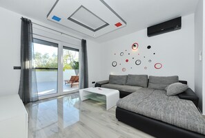 Un salon moderne avec un canapé, une table basse et une porte-fenêtre coulissante donnant sur un espace extérieur.