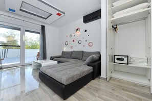 Quarto moderno com uma cama grande, uma mesinha, um guarda-roupa e uma parede com arte abstrata.