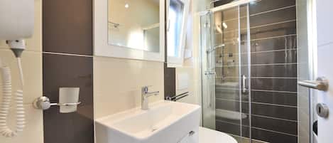 A modern bathroom with a glass shower enclosure, a white sink, and a toilet.