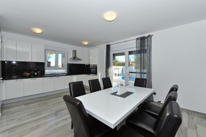 Une cuisine moderne avec des meubles blancs, un plan de travail noir et un coin repas comprenant une table blanche et des chaises noires.