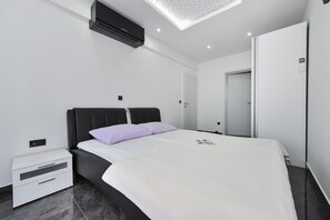 A modern bedroom with a bed, nightstand, and a wall-mounted air conditioner. - Villa Lily ZadarVillas (Privlaka)