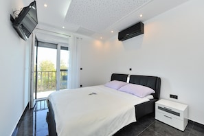 Une chambre moderne avec un lit, une table de chevet et un téléviseur fixé au mur.