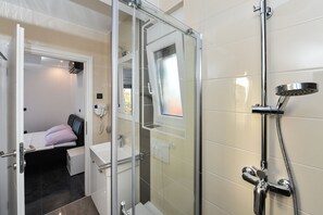 Une salle de bain moderne avec une douche à parois de verre, un lavabo intégré et une petite table de chevet avec un coussin.