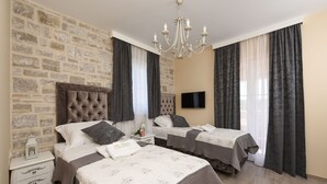 A hotel room with two beds, a stone wall, a chandelier, and a TV. - Villa Imperia ZadarVillas (Pridraga)