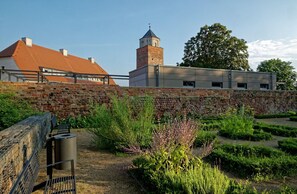 A courtyard with a brick wall, a tower, and a building with a red roof. - Maisonette Bad Camberg (Bad Camberg)