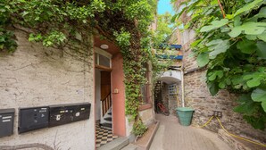 A narrow alleyway with a building entrance, a bicycle, and a green trash bin. - Maisonette Bad Camberg (Bad Camberg)