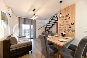Enjoy meals in this stylish dining area with a wooden table for four, a sofa, and comfortable chairs.