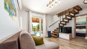 Una sala moderna con un sofá, un televisor y una escalera.