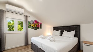 Un dormitorio con una cama, una mesita de noche, cortinas en la ventana y decoración en la pared.