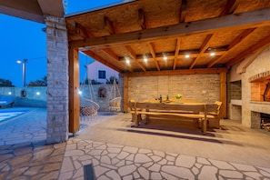 An outdoor patio area with a stone floor, wooden bench, and a brick wall. - Villa Kamen ZadarVillas (Pridraga)