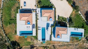 An aerial view of a modern resort with three large villas, each with a swimming pool and outdoor seating areas. - Villa Katerina Mentoros (Kefalonia)