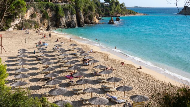 A beach with numerous sun umbrellas and people relaxing. - Villa Katerina Mentoros (Kefalonia)