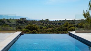 A clear blue infinity pool with a view of a lush landscape and distant mountains. - Villa Katerina Mentoros (Kefalonia)