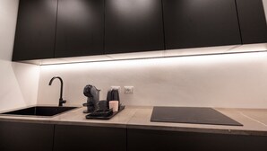 A modern kitchen with a sleek black countertop, a built-in sink, and a coffee machine. - La mia terra Boutique Rooms (Palermo)
