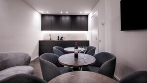 A modern living room with a round table, grey sofas, a wine bottle, and glasses. - La mia terra Boutique Rooms (Palermo)