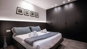 Un dormitorio moderno con una cama grande, paredes oscuras y un armario empotrado.