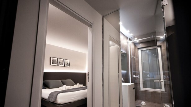 A modern bedroom with a bed, bedside tables, and a large mirror. - La mia terra Boutique Rooms (Palermo)