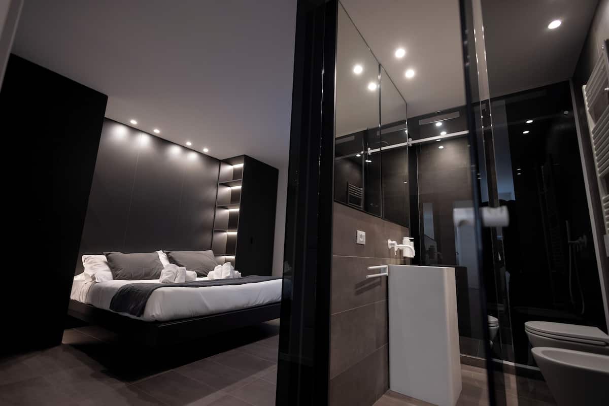 Une chambre à coucher moderne avec un lit, une douche en verre et une salle de bain au design minimaliste.