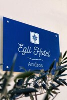 Un letrero azul con el texto 'Egli Hotel Andros' y un logotipo encima del texto.