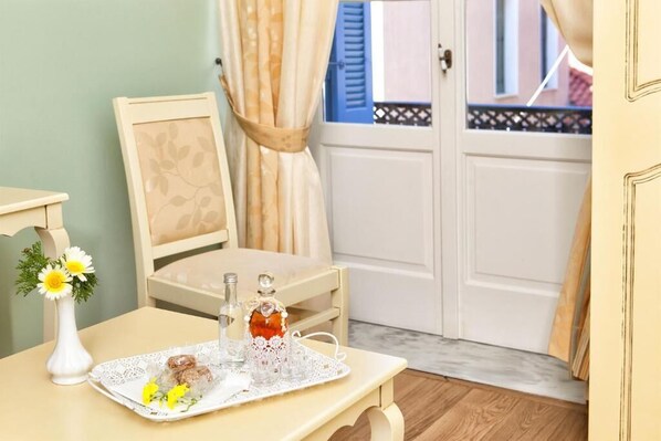 A neatly arranged room with a table set for breakfast, a chair, a vase with flowers, and a view of the outside through a door.